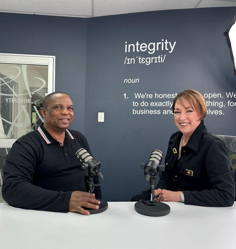 Peter Mehlape and another speaker at the Off The Clock studio table, two podcast microphones between them and the word 'integrity' on the wall behind